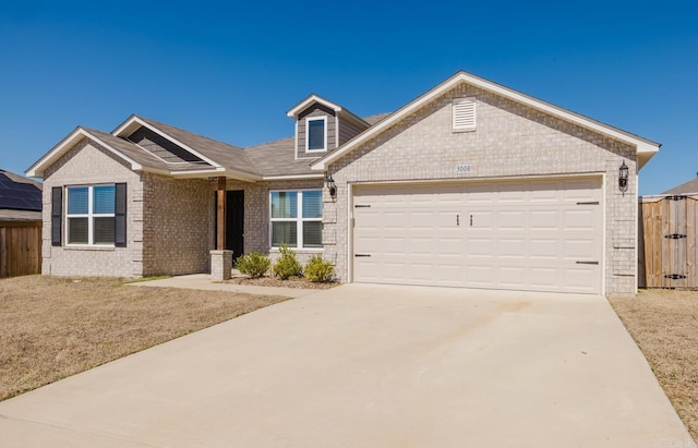 view of front facade featuring concrete driveway, fence, brick siding, and a garage