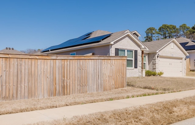 exterior space featuring a garage, brick siding, concrete driveway, and fence