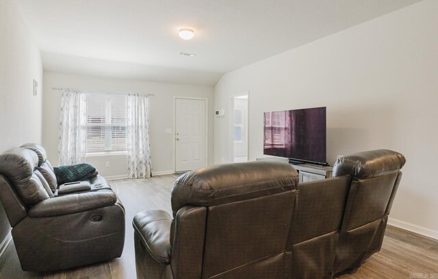 living room with vaulted ceiling, light wood-style floors, and baseboards