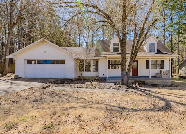 new england style home featuring covered porch, concrete driveway, and an attached garage