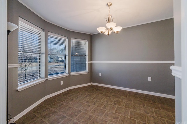 spare room with baseboards, an inviting chandelier, and crown molding