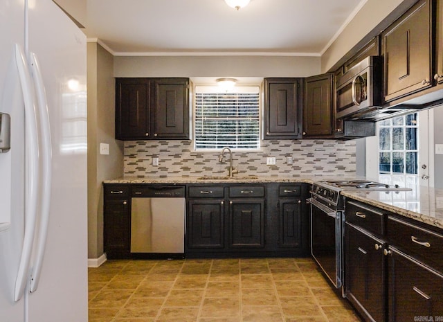 kitchen with light stone countertops, a sink, decorative backsplash, appliances with stainless steel finishes, and crown molding