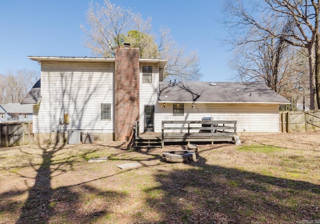 rear view of house featuring a yard, fence, a chimney, and a wooden deck