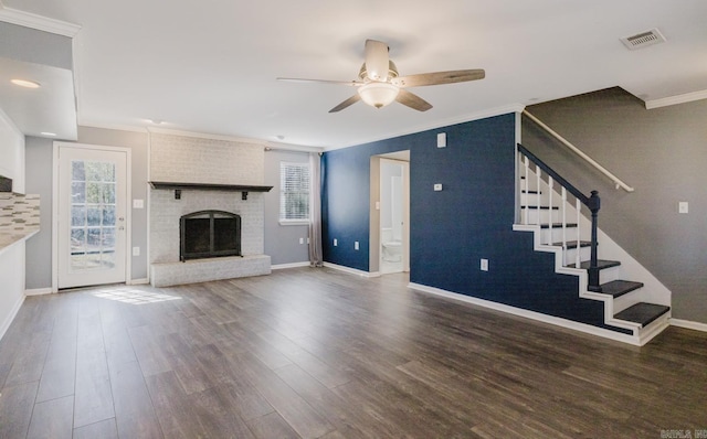 unfurnished living room with visible vents, crown molding, stairs, a fireplace, and wood finished floors