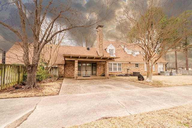 view of front of home featuring brick siding, driveway, and fence