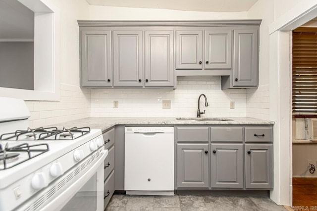 kitchen with tasteful backsplash, gray cabinets, white appliances, and a sink