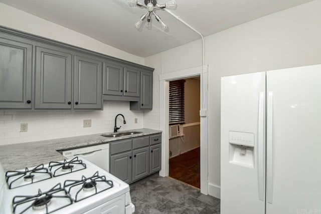 kitchen with white appliances, light stone counters, gray cabinets, a sink, and backsplash