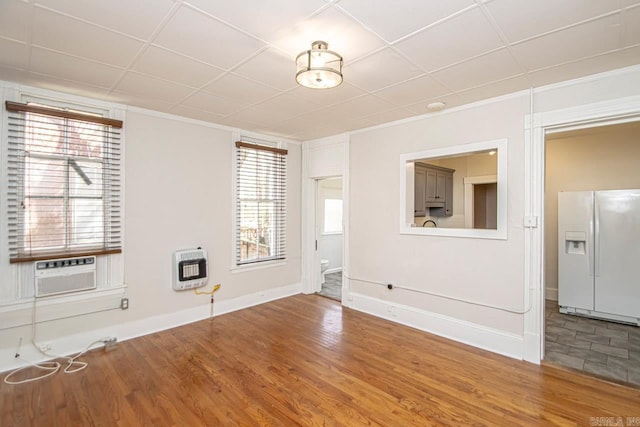 empty room with heating unit, baseboards, and wood finished floors