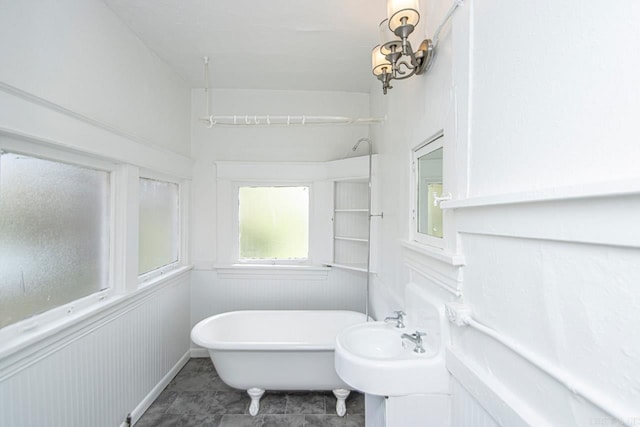 full bath featuring a soaking tub and a wainscoted wall