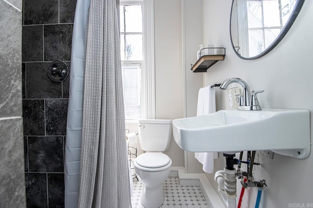 bathroom featuring a sink, tile patterned floors, toilet, and tiled shower