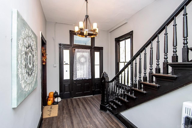 foyer entrance with stairs, a notable chandelier, and dark wood-style floors