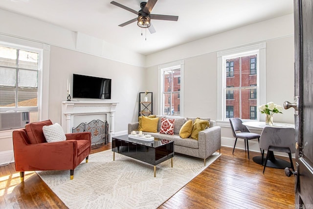 living area with hardwood / wood-style floors, cooling unit, baseboards, a fireplace, and ceiling fan