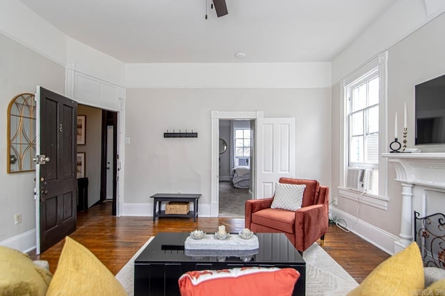 living area featuring cooling unit, a fireplace, baseboards, and wood finished floors