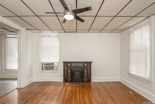 unfurnished living room featuring baseboards, a fireplace, wood finished floors, a paneled ceiling, and a ceiling fan