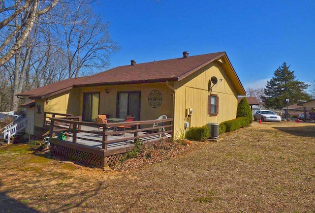 exterior space with central air condition unit, a lawn, and a wooden deck