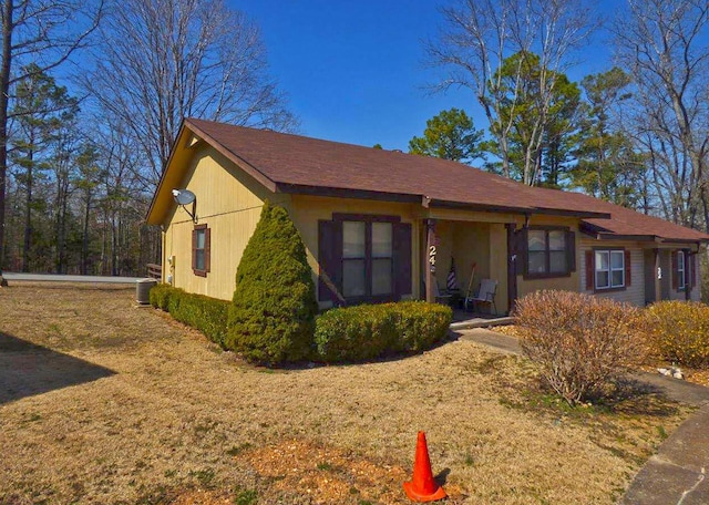 view of front of house with a front lawn and central AC