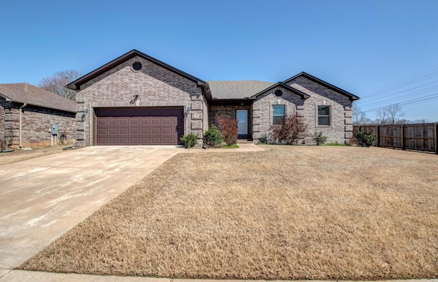 view of front of house featuring a front yard, fence, driveway, a garage, and brick siding