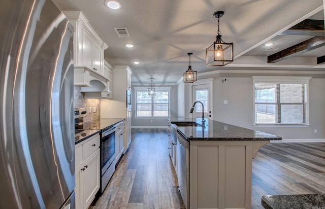 kitchen featuring visible vents, a center island with sink, a sink, backsplash, and appliances with stainless steel finishes