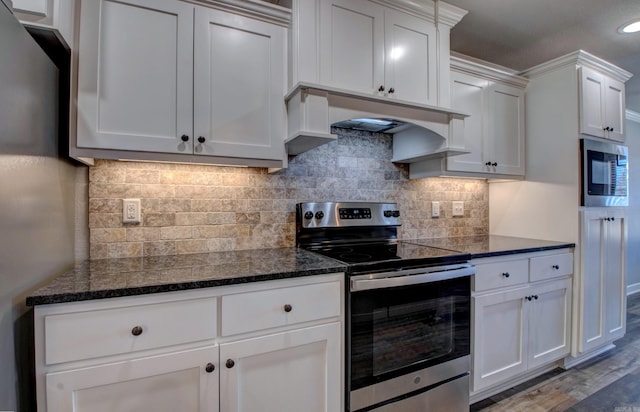 kitchen featuring dark stone countertops, ventilation hood, backsplash, and appliances with stainless steel finishes