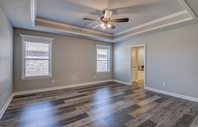 empty room with a raised ceiling, visible vents, dark wood-style flooring, and ornamental molding