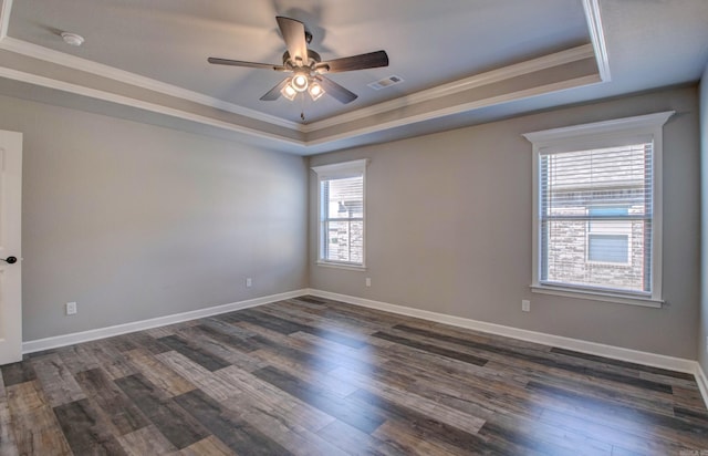 unfurnished room with baseboards, visible vents, dark wood-type flooring, crown molding, and a raised ceiling