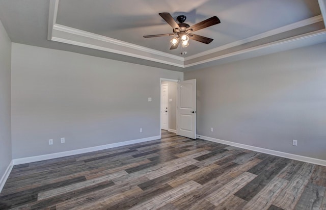 unfurnished room featuring dark wood-style floors, a raised ceiling, baseboards, and ornamental molding