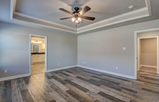 unfurnished bedroom with baseboards, a raised ceiling, ornamental molding, and dark wood-style flooring