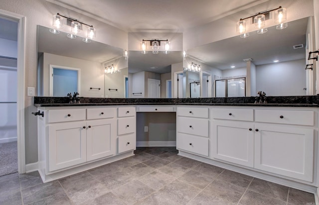 full bath featuring vanity, a shower with shower door, baseboards, and visible vents