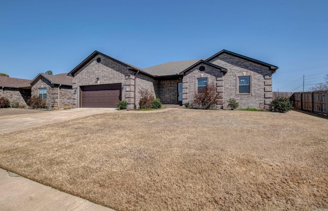 french country home with fence, driveway, an attached garage, a front lawn, and brick siding