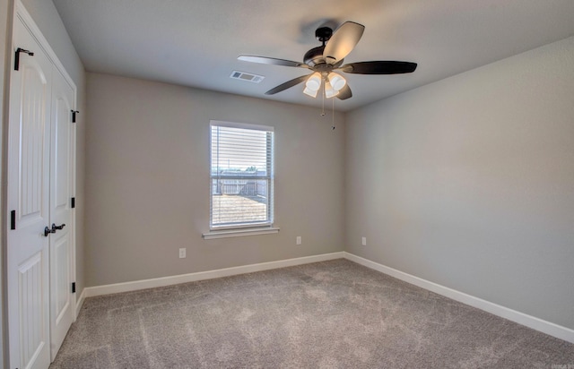 carpeted empty room with visible vents, ceiling fan, and baseboards