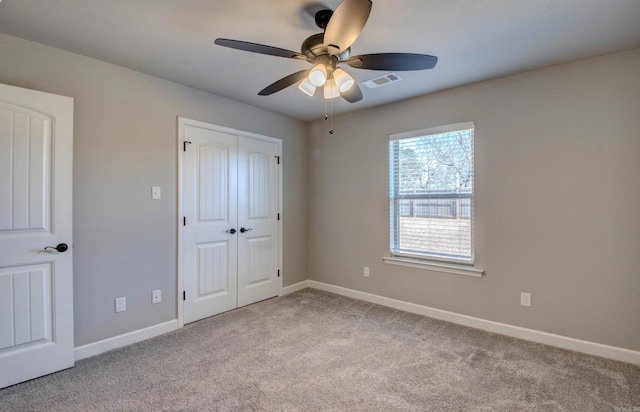 unfurnished bedroom featuring visible vents, a closet, carpet, baseboards, and ceiling fan