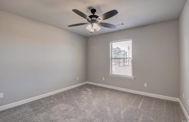 carpeted spare room with visible vents, a ceiling fan, and baseboards