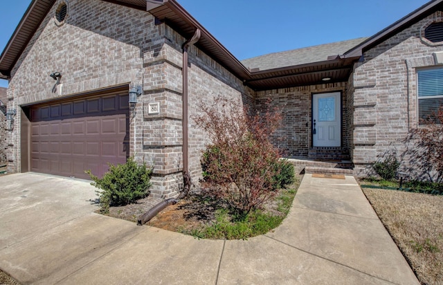 doorway to property with brick siding, concrete driveway, and a garage