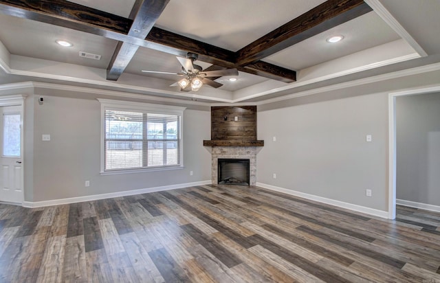 unfurnished living room featuring visible vents, baseboards, beamed ceiling, a stone fireplace, and wood finished floors