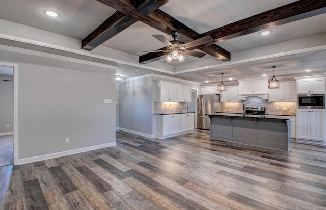 kitchen with baseboards, beamed ceiling, appliances with stainless steel finishes, wood finished floors, and white cabinets