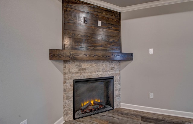 interior details with baseboards, a lit fireplace, wood finished floors, and ornamental molding