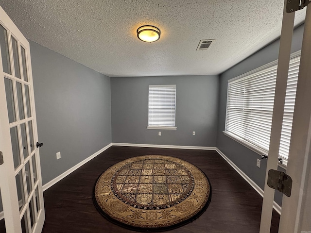 spare room with wood finished floors, visible vents, a wealth of natural light, and baseboards