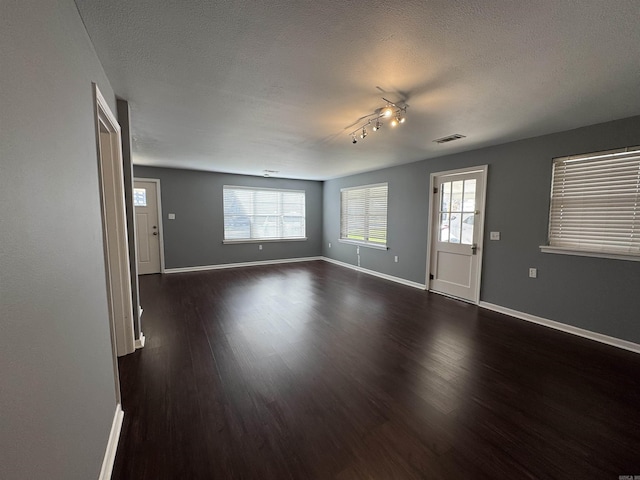 unfurnished living room featuring baseboards, a healthy amount of sunlight, and dark wood-style flooring