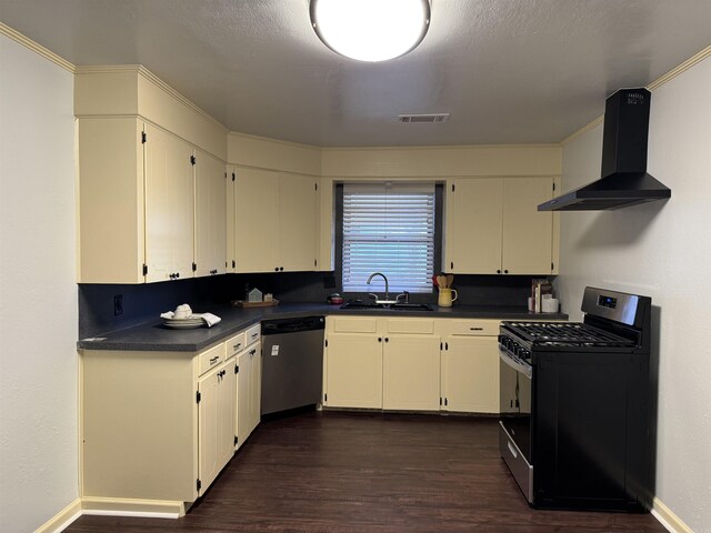 kitchen with visible vents, a sink, appliances with stainless steel finishes, dark countertops, and wall chimney exhaust hood