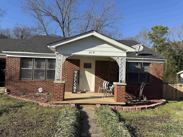 bungalow with a porch, brick siding, and a shingled roof