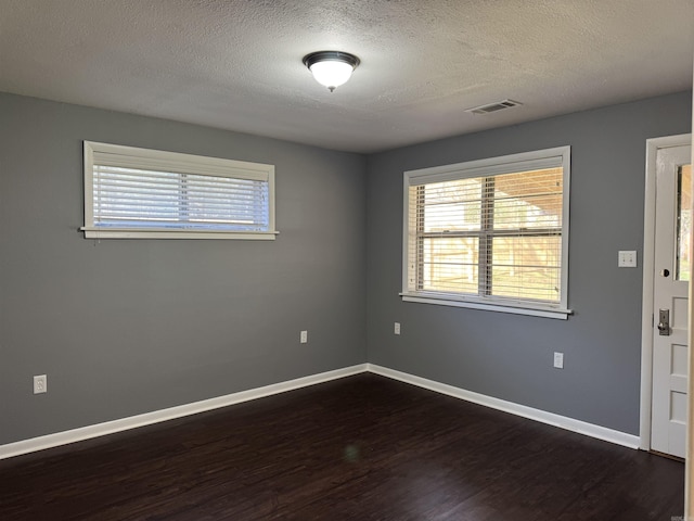 empty room with dark wood finished floors, a healthy amount of sunlight, and baseboards