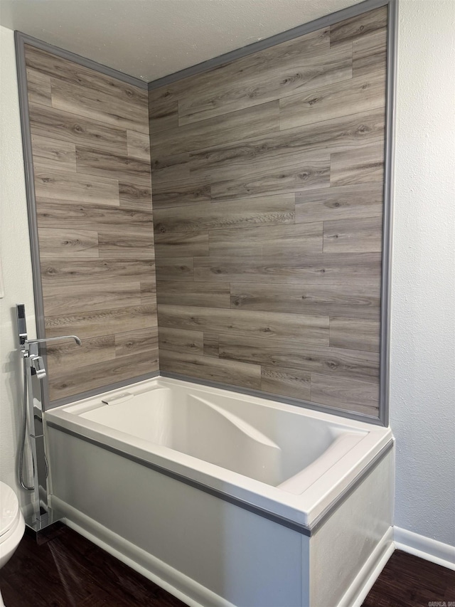 bathroom with baseboards, toilet, and wood finished floors