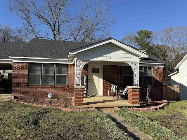 bungalow featuring brick siding, covered porch, and a shingled roof