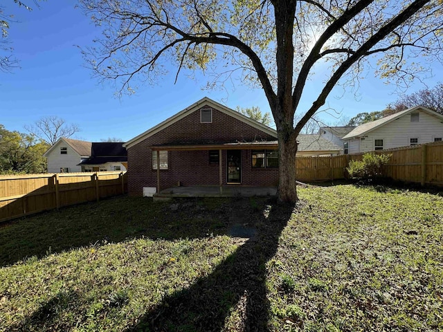 back of house with a patio, brick siding, a fenced backyard, and a lawn