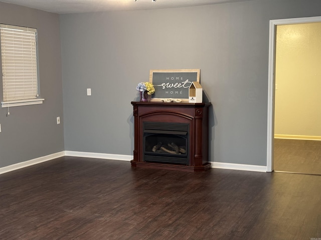 unfurnished living room with a fireplace, baseboards, and wood finished floors