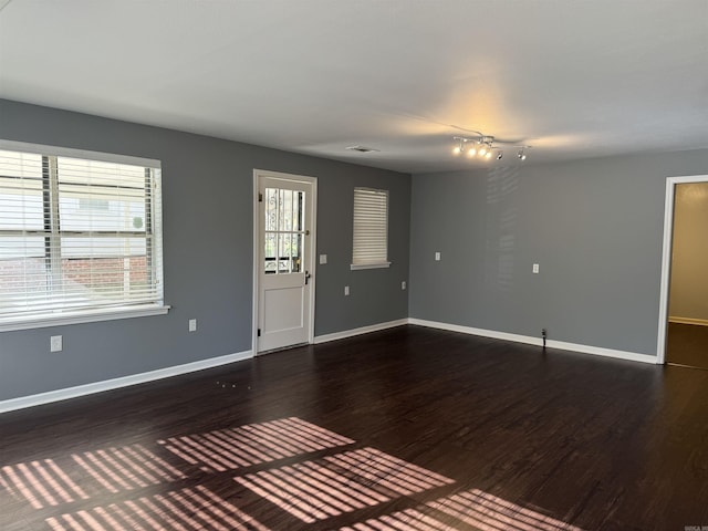 interior space with dark wood finished floors, visible vents, and baseboards