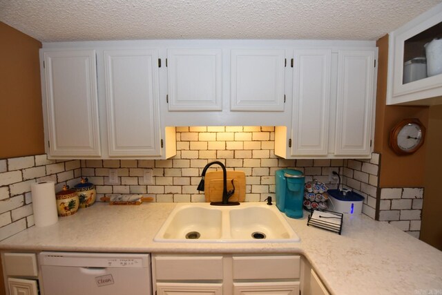 kitchen with dishwasher, light countertops, a textured ceiling, white cabinetry, and a sink