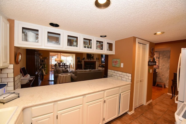 kitchen featuring white cabinetry, freestanding refrigerator, light countertops, light tile patterned floors, and glass insert cabinets