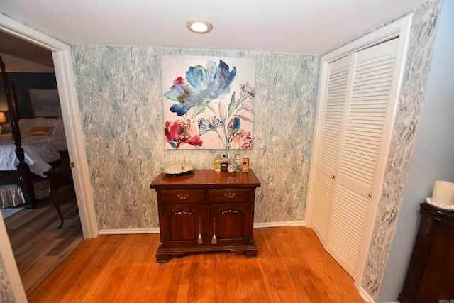 hallway featuring wallpapered walls, baseboards, and wood finished floors