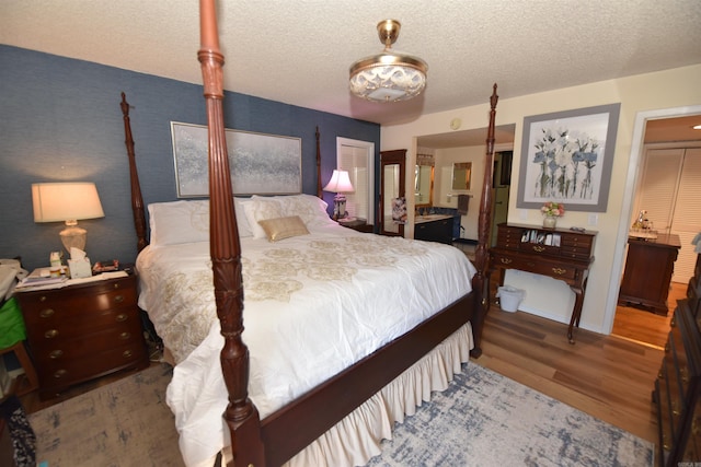 bedroom with connected bathroom, a textured ceiling, and wood finished floors